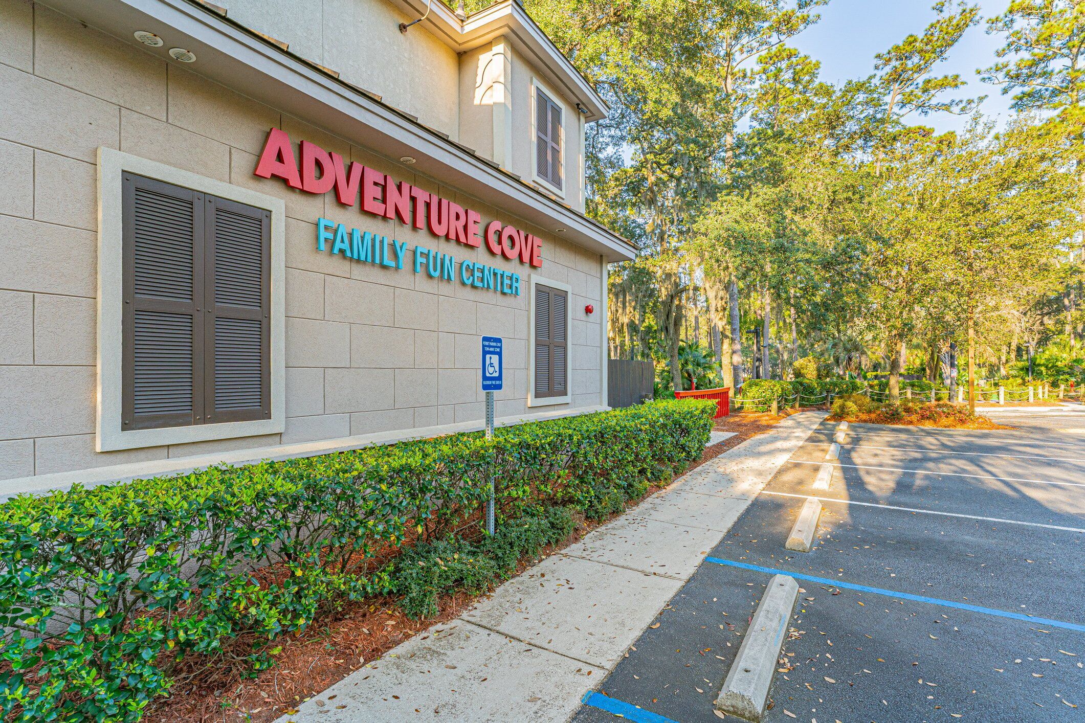Un edificio con un cartello che riporta la scritta "ADVENTURE COVE FAMILY FUN CENTER" e un parcheggio con il segnale blu per posti auto riservati ai disabili.