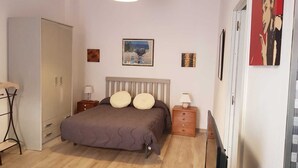 Une chambre à coucher comprenant un lit, des tables de chevet, une armoire et des œuvres d’art accrochées aux murs.