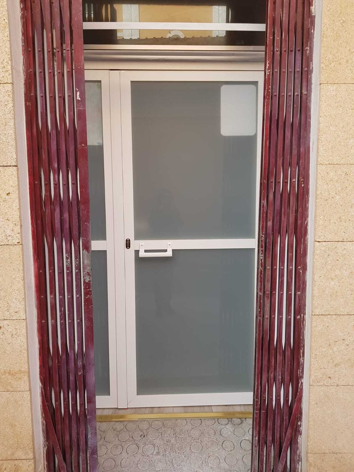 A closed glass door with a white frame and a handle, flanked by vertical metal bars.