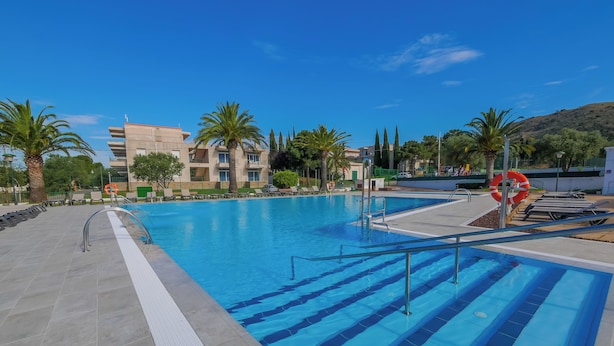 A swimming pool with clear blue water, surrounded by lounge chairs and palm trees.