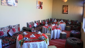 A traditional dining area with multiple tables and benches, each set with plates, glasses, and cutlery. - Auberge Benija (Anougal)