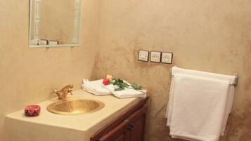 A bathroom with a toilet, sink, mirror, towel rack, and patterned rug.
