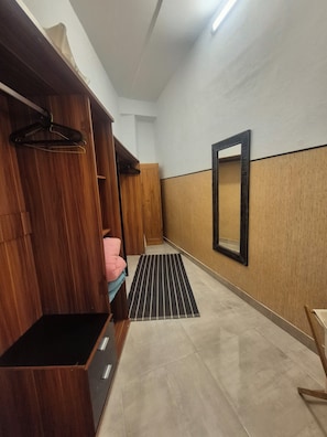 A hotel room with a wooden wardrobe, a black and white striped rug, a mirror on the wall, and a tiled floor. - Casa Hector good views (Arona)