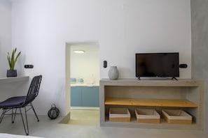 Un salon moderne avec un téléviseur, un fauteuil, une plante en pot et une petite table sur laquelle sont posés des paniers.