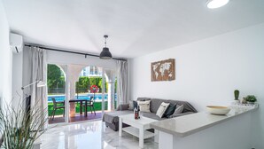 A modern living room with a sofa, coffee table, and a view of a pool.