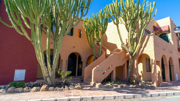 A building with a stucco exterior, arched windows, and a staircase leading to the entrance.