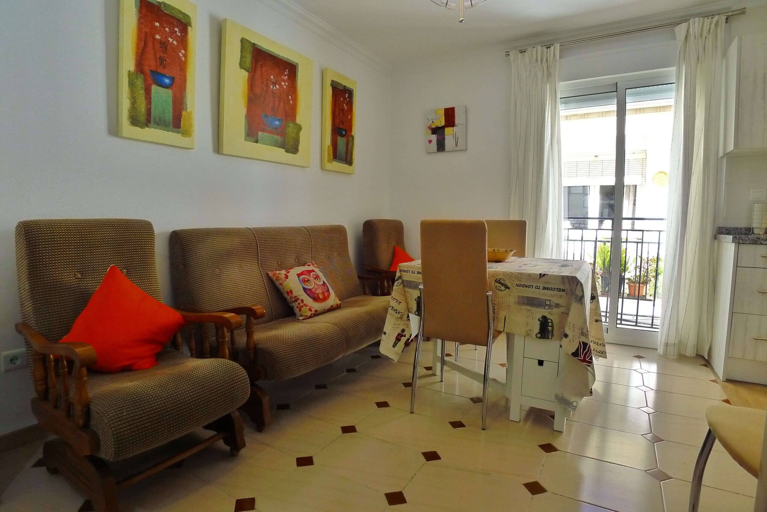 Ein Wohnzimmer mit einer Couch, Sesseln, einem kleinen Tisch und einem Balkon mit Blick.
