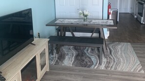 A modern kitchen with a built-in TV, a dining table with a marble top, and a fire feature below the counter.