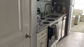 A kitchen with white cabinets, a microwave, a sink, and a stove.