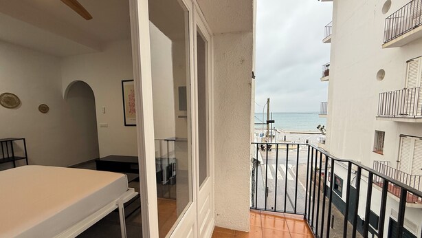 Een slaapkamer met een bed, een bureau en uitzicht op het strand.