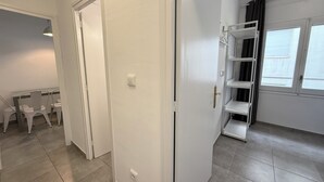 Een kamer met een witte deur, een witte wandplank en een raam met gordijnen.