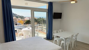 Une chambre d’hôtel comprenant un lit, une table, des chaises, une télévision et un balcon avec vue sur la ville.