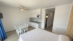 Une chambre d’hôtel de taille réduite comprenant un lit, une kitchenette, un coin repas et une salle de bain.