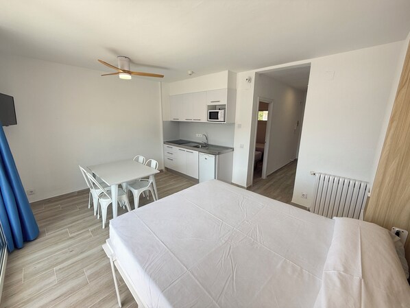 Une chambre d’hôtel de taille réduite comprenant un lit, une kitchenette, un coin repas et une salle de bain.
