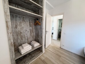 A room with a wooden wardrobe, a hanging clothes rack, and a neatly folded towel on the lower shelf. - Agi Rescator 202 Apartamento for rent in Roses Girona. (Rosas / Roses)