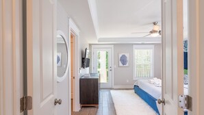 Een gang die leidt naar een slaapkamer met een bed, een kast en een spiegel bij de deur.