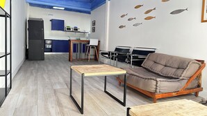 Una sala moderna con techo azul, un sofá marrón, una mesa de centro de madera y una cocina al fondo.