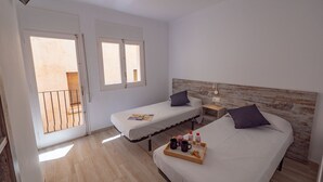 Un dormitorio con dos camas, cabeceros de madera, mesitas de noche con lámparas y una bandeja con bebidas y aperitivos.