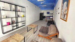 A compact living space with a kitchenette, a bookshelf, a sofa, and a small table.