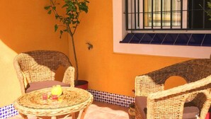 An outdoor patio with wicker furniture, a small table with a glass top, and a potted plant. - BUNGALOW WITH TERRACE 50M2,500M TO THE BEACH (Los Arenales del Sol)