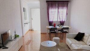 A living room with a TV, sofa, and a dining area with chairs and a table. - BUNGALOW WITH TERRACE 50M2,500M TO THE BEACH (Los Arenales del Sol)