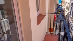 Un pasillo estrecho con una pequeña ventana y una barandilla de metal.