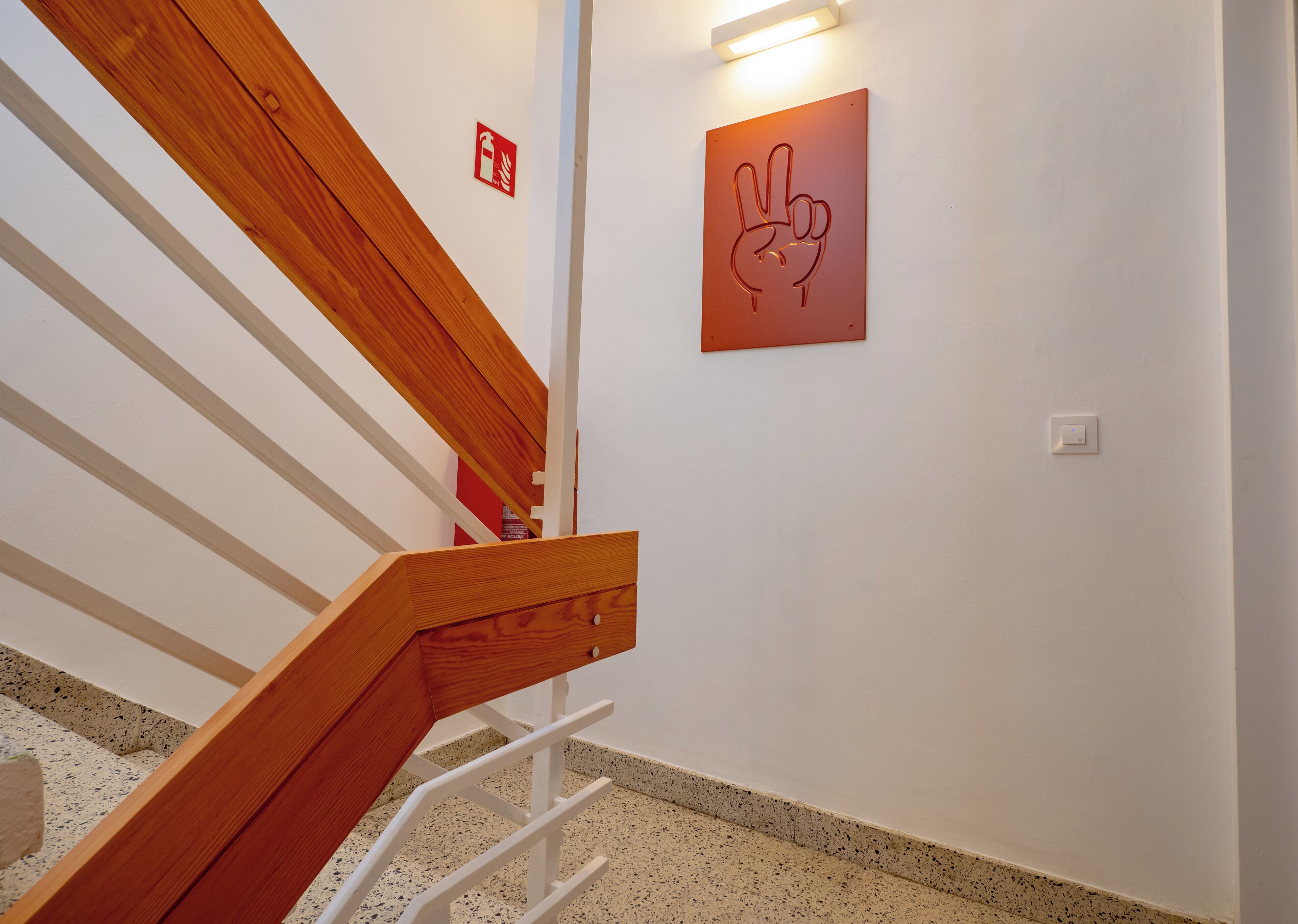 Un escalier avec des rampes en bois et un panneau en forme de main fixé au mur.
