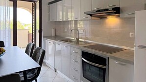 Una cocina moderna con armarios blancos, un lavamanos de acero inoxidable y un horno empotrado.