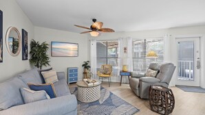 Ein Wohnzimmer mit Sofa, Sesseln, Couchtisch und Deckenventilator.