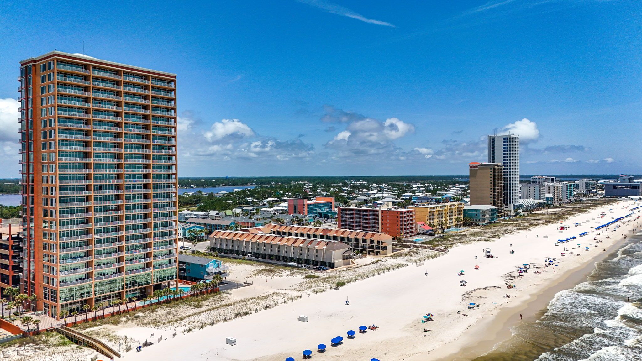 A coastal hotel with multiple floors, a beachfront, and a view of the ocean.