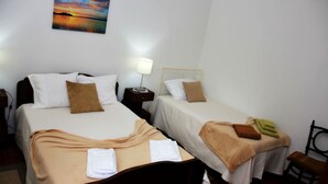 Une chambre d’hôtel avec deux lits, une table de chevet, une lampe et un tableau au mur.
