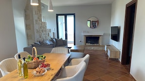 Un salon moderne avec une cheminée, un coin repas avec une table et des chaises en bois, et un mur en pierre.