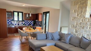 Un salon moderne avec un canapé d’angle gris, une table basse en bois et un coin repas comprenant une table et des chaises.