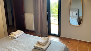Une chambre d’hôtel avec deux lits, un grand miroir, un radiateur, une porte-fenêtre coulissante donnant sur le balcon et un climatiseur fixé au mur.