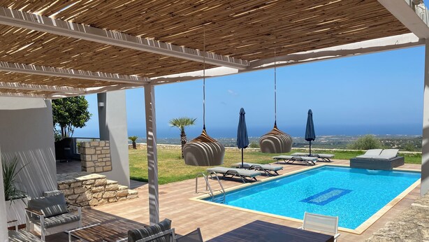 Un espace piscine aménagé avec des chaises longues, une table et des parasols.