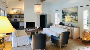 A living room with a fireplace, a large painting, and a wooden ceiling beam. - Modern Provencal Villa -  (Ramatuelle)