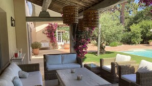 An outdoor patio with wicker furniture, a pool, and lush greenery. - Modern Provencal Villa -  (Ramatuelle)