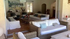 A spacious living room with a large painting, a dining area, and a view of the outdoors. - Modern Provencal Villa -  (Ramatuelle)