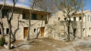 A stone building with multiple windows and doors, surrounded by trees.