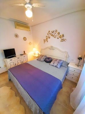 A bedroom with a bed, bedside tables, a TV, and decorative wall art.