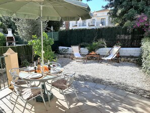 An outdoor patio with a round table, chairs, and an umbrella.