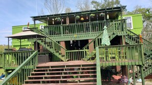 A green multi-level building with outdoor seating and stairs.