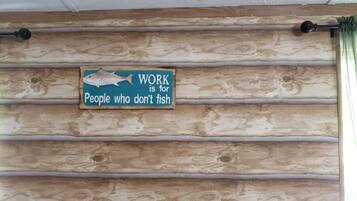 A wooden wall with horizontal planks and a sign that reads 'WORK is for People who don't fish.'