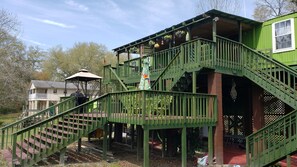 A green metal staircase leading to a covered outdoor area with a gazebo and potted plants.