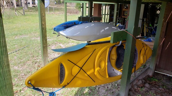 A yellow kayak with a grey top, secured under a wooden structure.