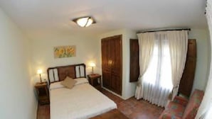 A bedroom with a bed, bedside tables, a wooden wardrobe, a chair, and a window with curtains. - Asque: House with garden (Asque)