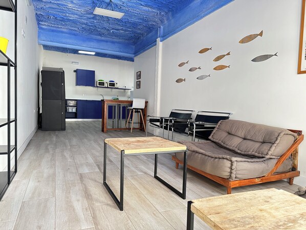 Een moderne woonkamer met een blauw plafond, een bruine bank, een houten salontafel en een keuken op de achtergrond.