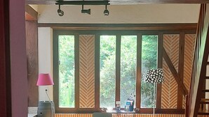 A dining area with a long table, chairs, and a stone floor. There are windows with a view of greenery outside. - Comfortable Solognote house for a pleasant family holiday (Dhuizon)