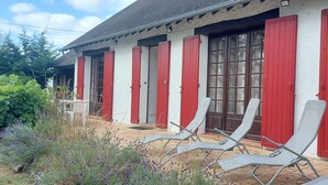 A building with red shutters and a tiled patio with lounge chairs. - Comfortable Solognote house for a pleasant family holiday (Dhuizon)