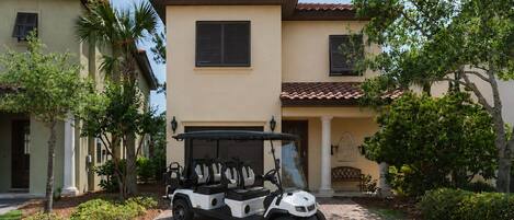 A golf cart parked in front of a building with a tiled roof and a garage door.
